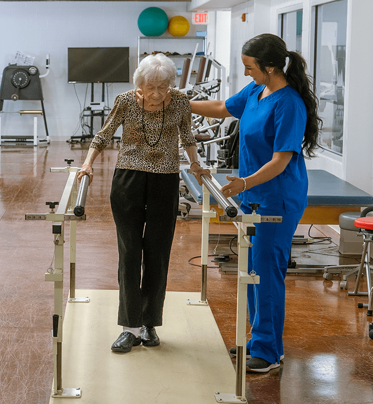 Patient walking on balance bars with help in a skilled nursing facility